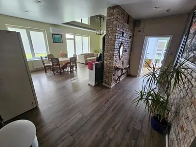 a living room with wooden floors and a brick wall at Apartamentai keliaujantiems į Kauna in Garliava