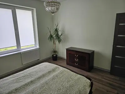 a bedroom with a bed and a dresser and a window at Apartamentai keliaujantiems į Kauna in Garliava