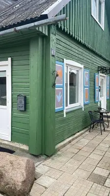 a green building with a bench in front of it at Jolantos svečių namai in Rokiškis