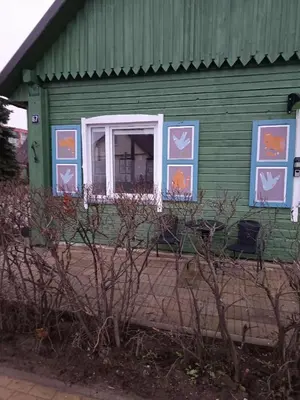 a green house with paintings on the side of it at Jolantos svečių namai in Rokiškis