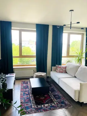 a living room with a white couch and blue curtains at Floral Sunshine Apartment in Vilnius