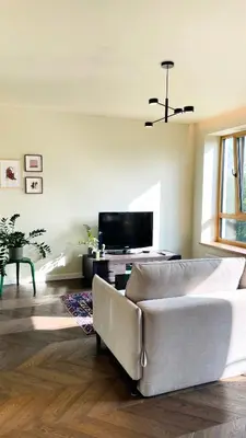 a living room with a couch and a tv at Floral Sunshine Apartment in Vilnius