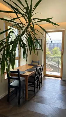 a wooden table with chairs and a large plant at Floral Sunshine Apartment in Vilnius