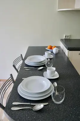 a table with white plates and silverware on it at Green House Apartment in Kaunas