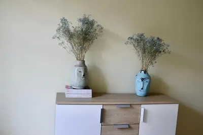 two vases sitting on top of a cabinet with flowers at Green House Apartment in Kaunas
