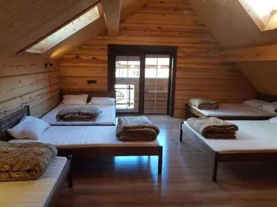 a room with four beds in a wooden cabin at Namas su pirtimi Trakai in Salkininkai