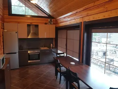 a kitchen with a table and chairs and a refrigerator at Namas su pirtimi Trakai in Salkininkai