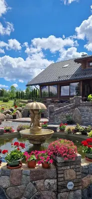 a fountain in the middle of a garden with flowers at Namas su pirtimi Trakai in Salkininkai