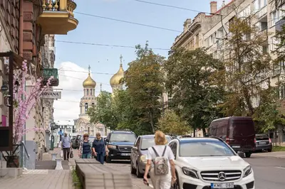 a woman walking down a city street with cars at Spacious Apartment In Vilnius Old Town by Reside Baltic in Vilnius