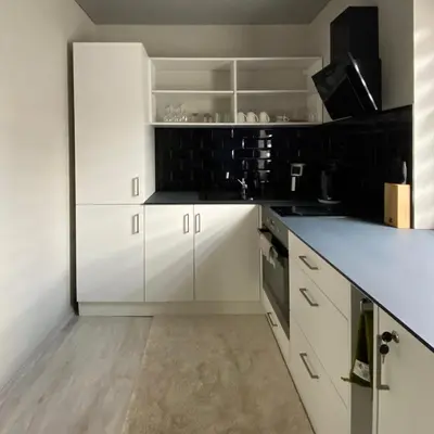 a white kitchen with white cabinets and black tiles at Čiurlionio 14 in Kaunas