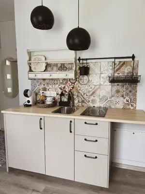 a kitchen with white cabinets and black pendant lights at Vilties vila in Anykščiai