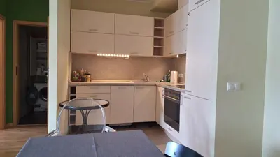 a small kitchen with white cabinets and a table at Butas1 in Vilnius