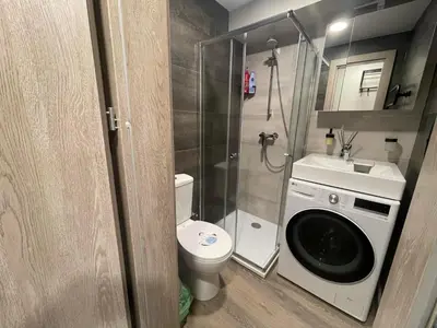 a small bathroom with a toilet and a washing machine at 24h self check-in COZY VISIT Studio3 on the first floor in Kaunas
