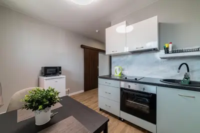 a kitchen with white cabinets and a sink and a table at Svečių namai Imperija in Šiauliai