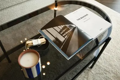a glass table with a book and a cup of coffee at River home in Kaunas