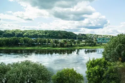 a river with trees and clouds in the sky at River home in Kaunas
