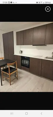 a kitchen with brown cabinets and a table and a sink at VV apartamentai in Kaunas