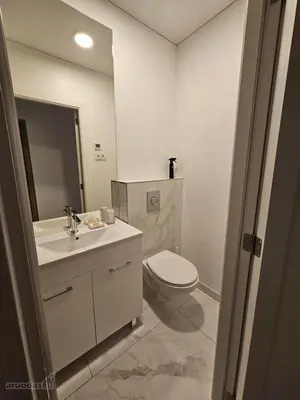 a white bathroom with a toilet and a sink at VV apartamentai in Kaunas