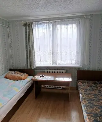 a room with two beds and a table and a window at Cosy Charming Guest House in central of Marijampole in Marijampolė