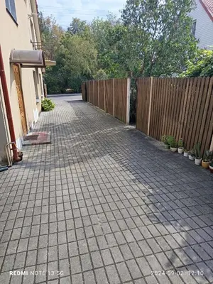 a driveway with a fence in a backyard at Cosy Charming Guest House in central of Marijampole in Marijampolė