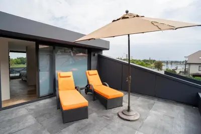 a balcony with two chairs and an umbrella at MARVEL apartamentai in Kaunas