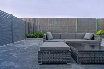 a patio with a couch and a table and a fence at MARVEL apartamentai in Kaunas