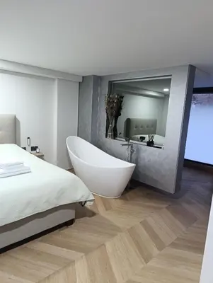 a bedroom with a white tub and a large mirror at MARVEL apartamentai in Kaunas