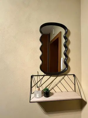 a mirror hanging on a wall with a shelf at Central Modern Two Bedroom Apartment in Druskininkai