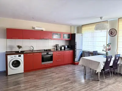a kitchen with red cabinets and a table with chairs at Central Modern Two Bedroom Apartment in Druskininkai