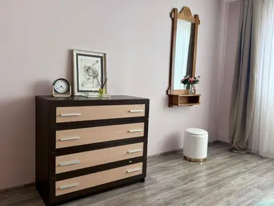 a dresser with a clock and a mirror in a room at Central Modern Two Bedroom Apartment in Druskininkai