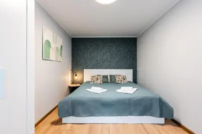 a bedroom with a bed with a blue blanket at Cozy Coner Apartments in Kaunas