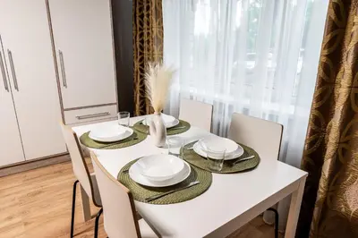 a white dining room table with white plates and chairs at Cozy Coner Apartments in Kaunas