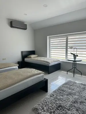a bedroom with two beds and a table and a window at Apartamentai LUKA in Marijampolė