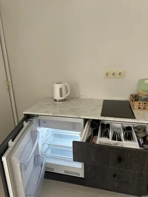 an empty refrigerator with its door open in a kitchen at Apartamentai LUKA in Marijampolė