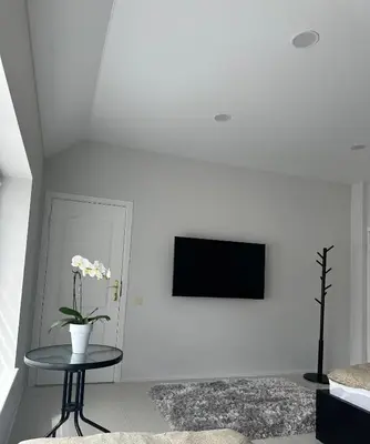 a white living room with a table and a tv at Apartamentai LUKA in Marijampolė