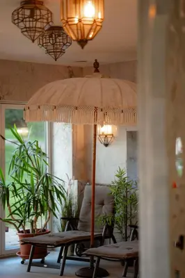 a table with an umbrella in a room with plants at Shanti Resort & Deluxe SPA in Sarboriškės I