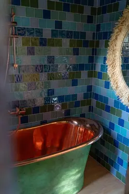 a tub in a bathroom with blue and green tiles at Shanti Resort & Deluxe SPA in Sarboriškės I