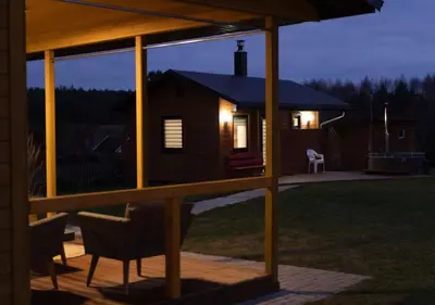 a porch with chairs and a house at night at GobeHouse Sodyba in Vilkanastrai