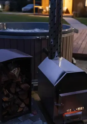 a wood fired oven with a pile of wood at GobeHouse Sodyba in Vilkanastrai