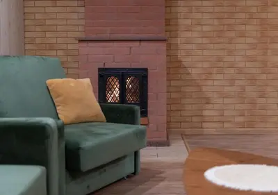 a green chair sitting in front of a brick fireplace at GobeHouse Sodyba in Vilkanastrai