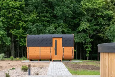 a tiny house with a black roof in a park at Poilsio Vingis in Liūnai