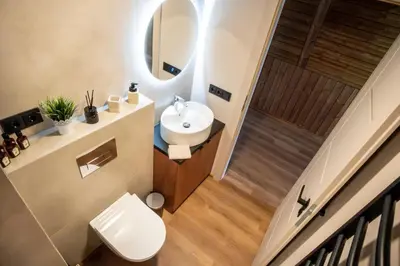 a bathroom with a white toilet and a sink at Poilsio Vingis in Liūnai
