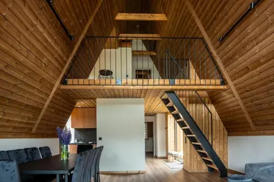 a large room with a wooden ceiling and a staircase at Poilsio Vingis in Liūnai