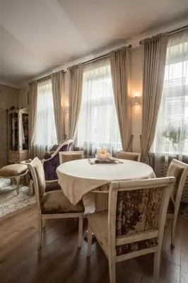 a living room with a table and chairs and windows at Boutique Classic Apartment in Kaunas Center in Kaunas