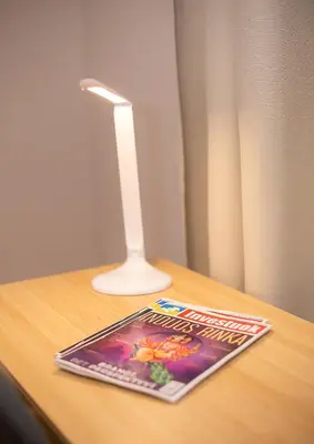 a book and a lamp on a table with a magazine at Šviesus ir jaukus butas Šiaulių centre puiki vieta poilsiui #2 in Šiauliai