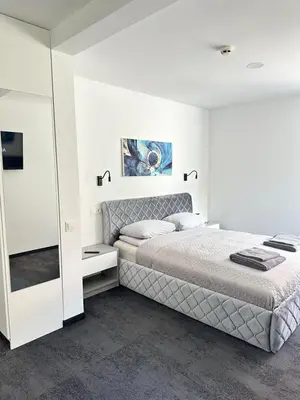 a white bedroom with a bed and a mirror at SILVIA apartment 101 in Druskininkai