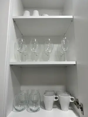 a row of wine glasses and cups on a shelf at SILVIA apartment 101 in Druskininkai