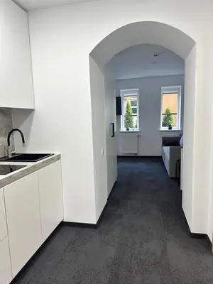 an empty kitchen with white cabinets and a hallway at SILVIA apartment 101 in Druskininkai