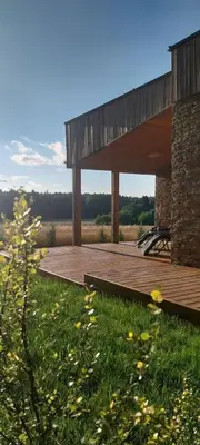 a building with a wooden deck in the grass at Mango namelis in Žuvininkai