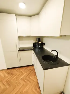 a kitchen with white cabinets and a black counter top at Cozy Noko Apartments in Kaunas